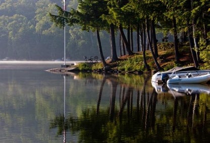 Boat sitting on the water near some trees in a beautiful lake