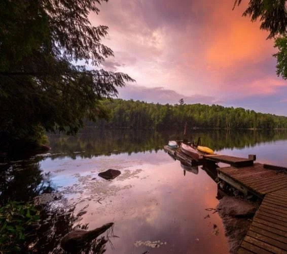Dock leading up to a lake during sunset with orange and purple skies