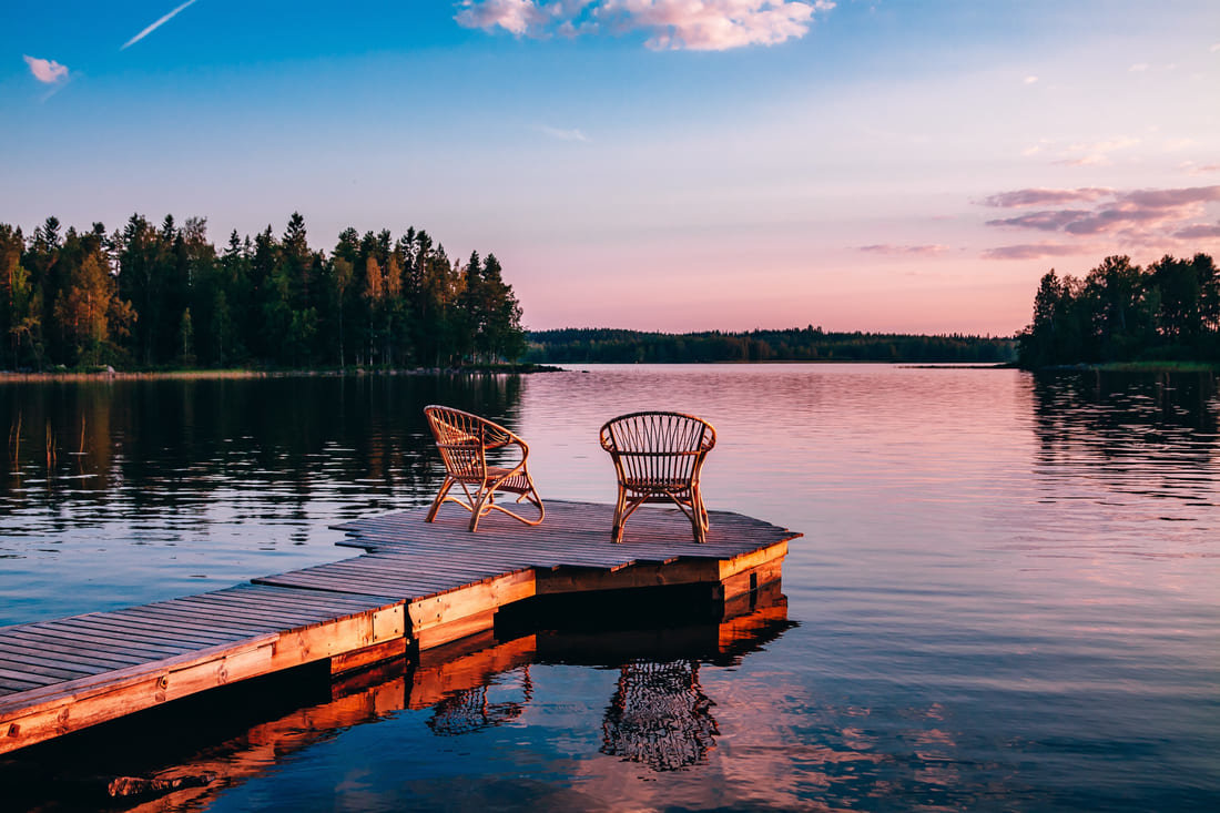 A Muskoka, Ontario dock by a lake with chairs