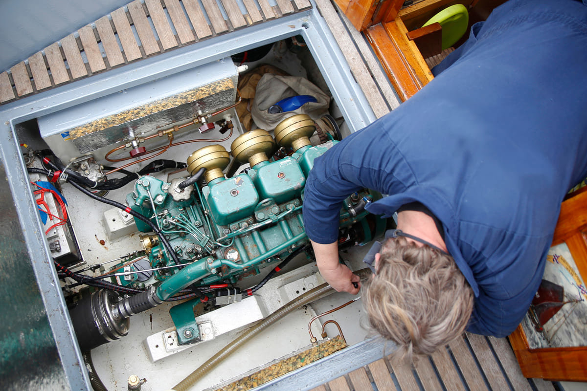 A boat mechanic working on an engine during the day.