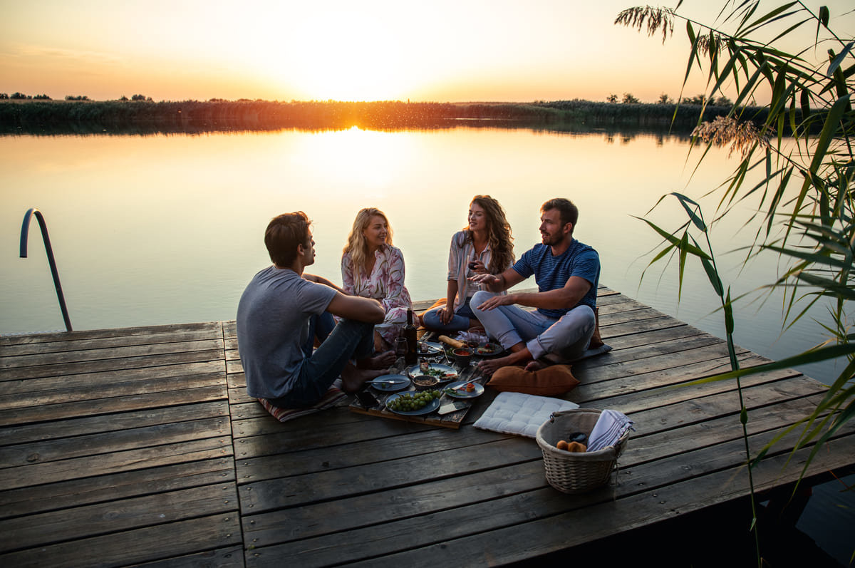 Friends having a meal sitting on a dock.