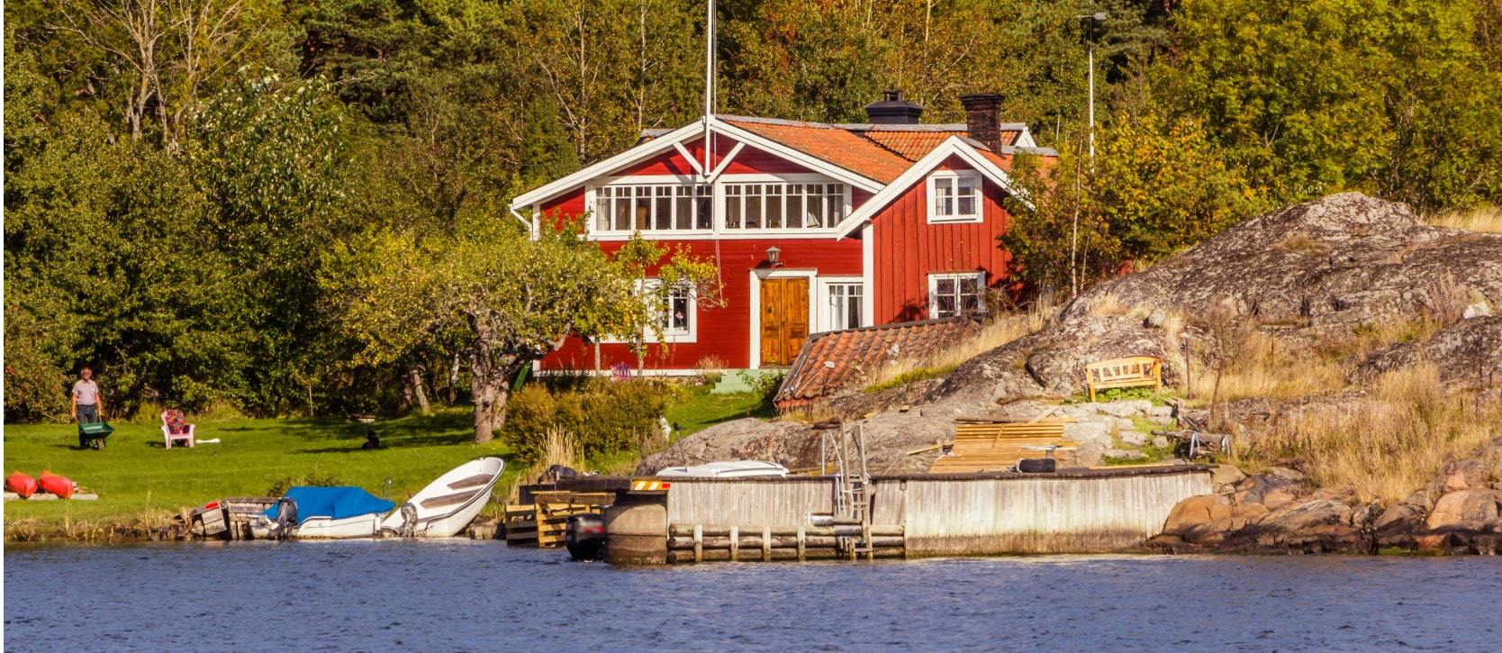 Red cottage sitting on the water's edge of a lake