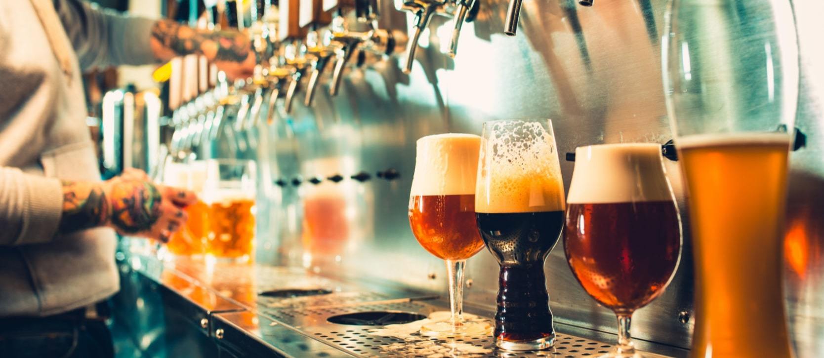 Drinks lined up behind the bar at the taps in a brewery