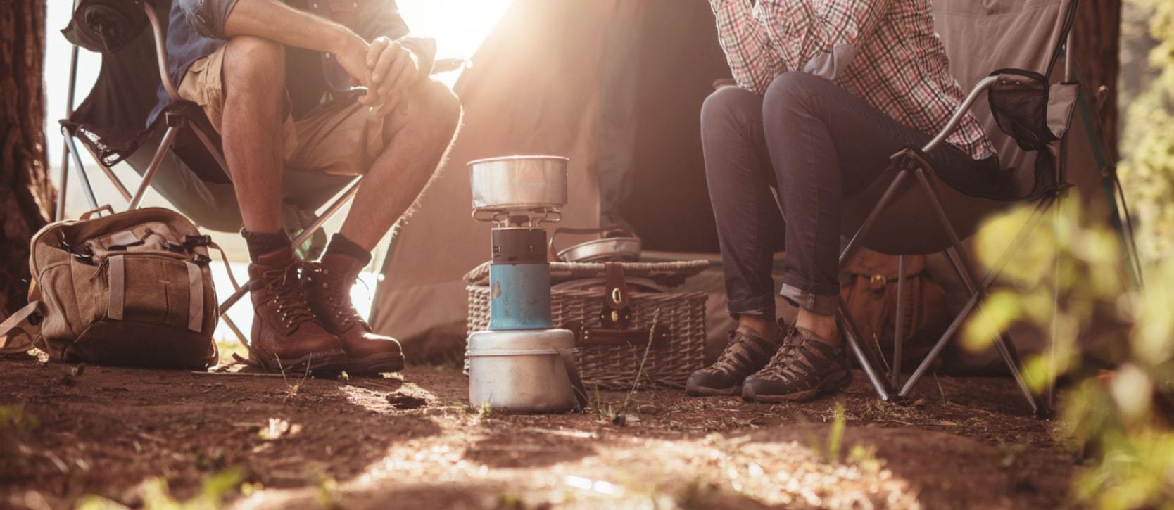 Two people sitting around a campsite talking 